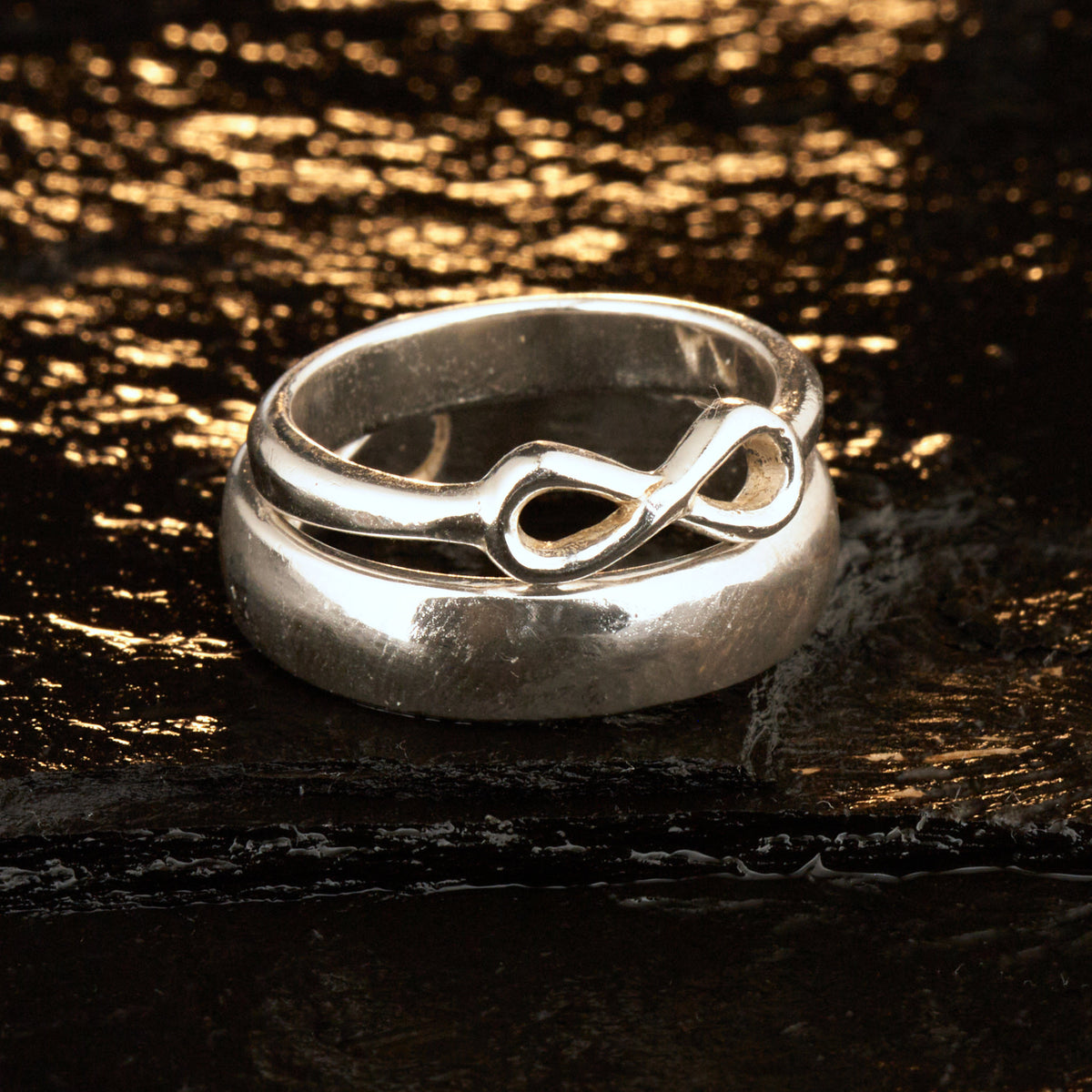  Handgefertigter Statement-Partnerring aus poliertem 925 Silber von Silberschweif mit großer Unendlichkeitsschleife (6x14mm). Die Schiene verjüngt sich elegant zum Motiv. Massiver 6mm Herrenring aus Silber. In der Innenansicht zeigt sich das fest eingravierte Unendlichkeits-Symbol als geheimes Zeichen der Verbundenheit.  Das Partnerring-Set „Ewigkeit“ zeigt das plastische Design des Damenrings und die spiegelnde Oberfläche des massiven Herrenrings